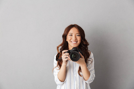 活泼开朗的亚洲女人站在灰色背景上，用照相相机拍照