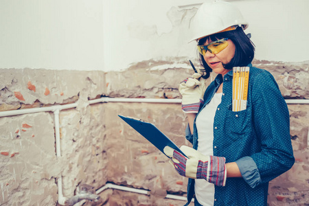 女建筑工人计划如何以积极的态度修理浴室管道。 使用工作工具。