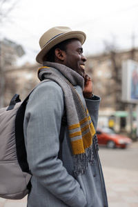 快乐的非裔美国人通过智能手机与他的朋友在城市散步