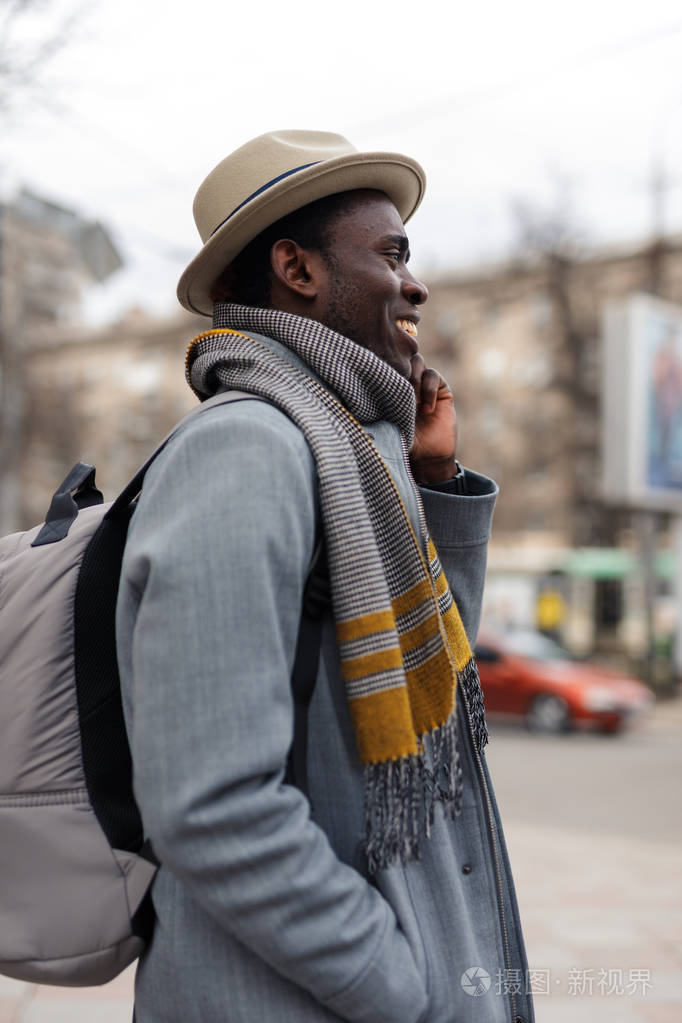 快乐的非裔美国人通过智能手机与他的朋友在城市散步