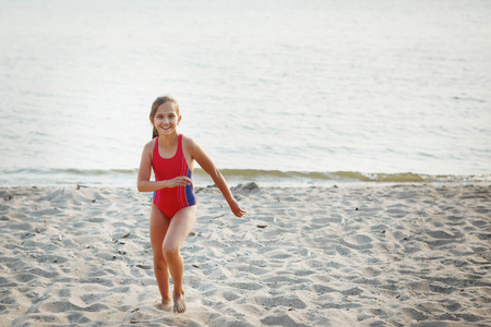 穿着红色泳衣在沙滩上海边奔跑的少女