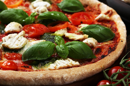 带西红柿的披萨，莫扎雷拉奶酪，黑色橄榄和罗勒。 木制比萨饼板上美味的意大利披萨。 意大利披萨