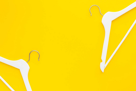 创意顶部视图平躺白色木制衣架孤立大胆的黄色背景与复制空间极简主义风格。 模板时尚女性博客社交媒体销售商店促销设计购物概念
