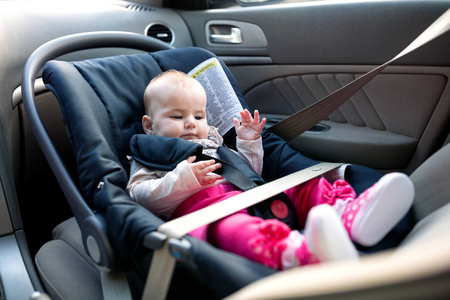 一个小女孩坐在她舒适的婴儿车座椅上安全开车
