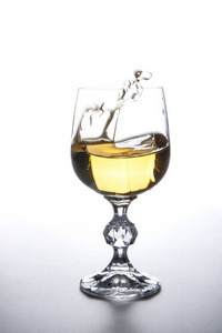 饮料和饮料概念。 白葡萄酒溅入酒杯中，动态滴入淡背景
