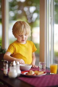 小男孩在旅馆餐馆吃健康的早餐。 在家里吃美味的饭菜。 儿童健康食品。
