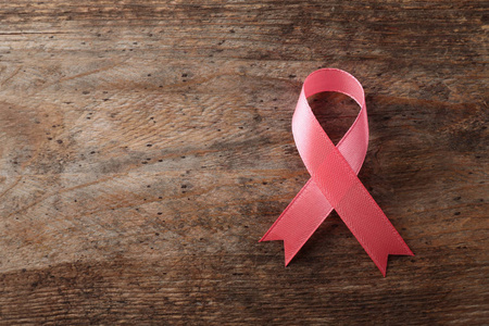 粉红色丝带在木制背景顶部视图与空间的文本。 乳腺癌意识概念