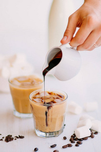 桌子上有 Marshmelow 和咖啡豆。夏日饮品。带牛奶和巧克力的冷咖啡。光背景。冰咖啡。冷却饮料的概念