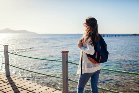 年轻的女游客背着背包欣赏红海和蒂兰岛的风景,走在码头上. 旅行概念.