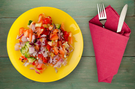 素食食品。 蔬菜沙拉胡椒番茄洋葱西兰花在盘子里。 木制背景的纯素沙拉