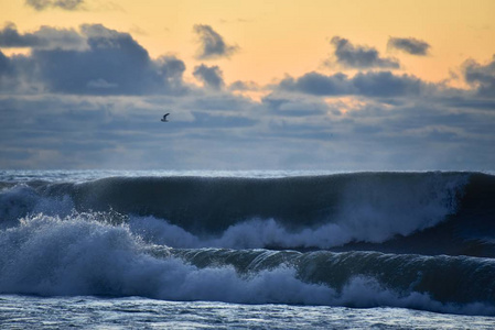 海上风暴。 巨浪涌进海岸。 地平线上的日落天空。