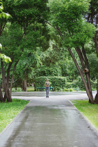 年轻女子沿着绿色公园的小径慢跑