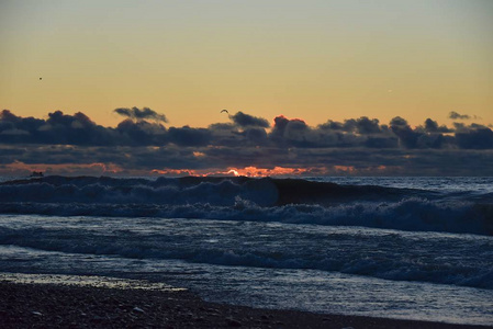 海上风暴。巨浪从海岸涌来.地平线上日落的天空。
