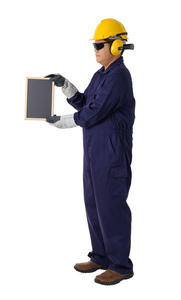 一名工人的全身肖像，戴着头盔耳罩防护手套和安全护目镜，手持白色背景剪裁路径上的黑板