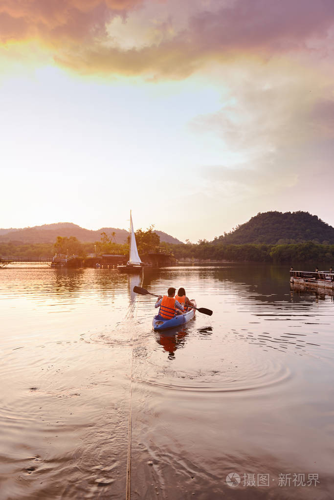 大型水库中的帆船人们以皮划艇为背景.日落时间