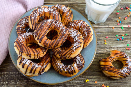 自制经典甜甜圈与巧克力和椰子片在木制背景。