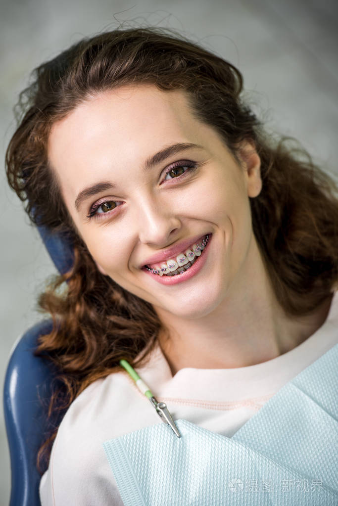 戴牙套的开朗女人在牙科诊所检查时微笑