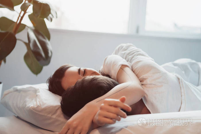 年轻夫妇在阳光下睡觉时拥抱