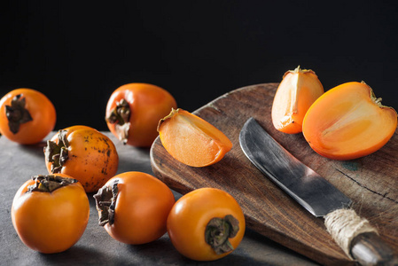用刀切割板上成熟和橙色的柿子
