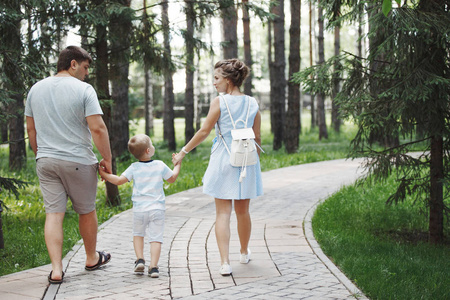 幸福的家庭在公园的石头路面上散步，重点是前景