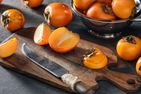 切片和整个橙色柿子在切割板和科兰德。