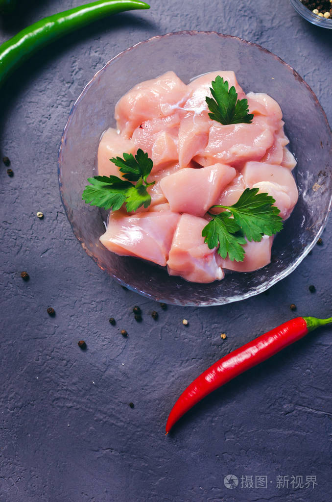 在黑暗的石头桌上的碗里的生鸡块.乳房立方体.顶视图照片-正版商用图