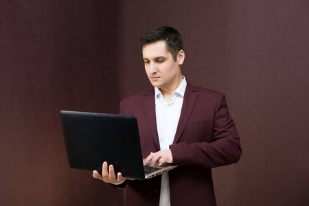 英俊的男人，黑发，电脑，穿着勃艮第服和牛仔裤。