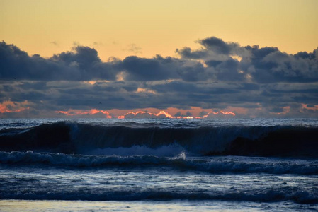 海上风暴。 巨浪涌进海岸。 地平线上的日落天空。