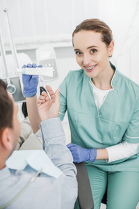 有吸引力的牙医有选择性地专注于微笑，同时拿着牙膏靠近病人