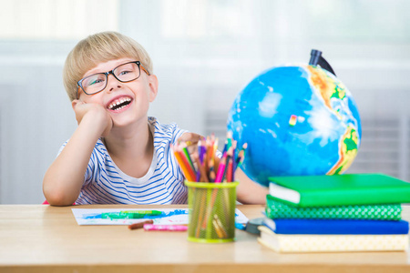 可爱的孩子在家学习。 有地球仪和书的小男孩在室内。 可爱的学生学习课程，做任务