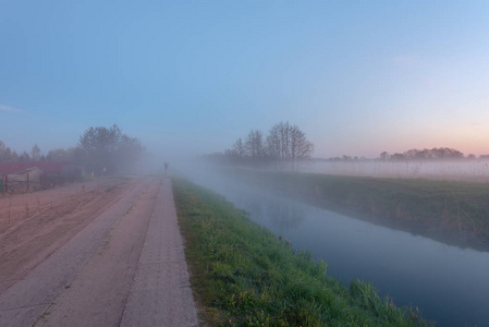日落时分，在河边的一片田野里，神秘的雾蒙蒙的夜晚。 波兰的Karwia村。