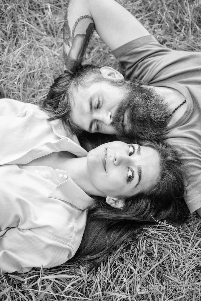 情侣在爱放松躺在草地上。大自然充满了清新与安宁。时髦的大胡子男人和女孩快乐无忧无虑的享受大自然。男子刮胡子和女孩躺在草地上。单独