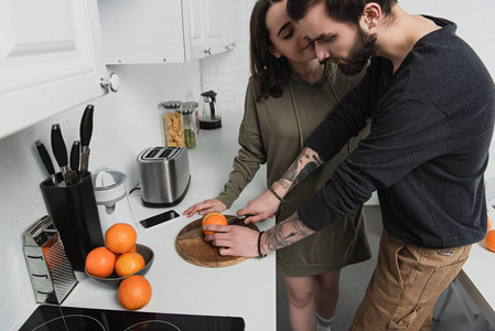 在厨房吃早餐的时候，男人和女人在木板上切橘子