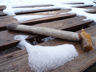 一把生锈的锤子放在覆盖着雪的老式木制背景上