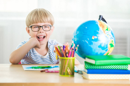 可爱的孩子在家学习。 有地球仪和书的小男孩在室内。 可爱的学生学习课程，做任务