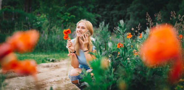 金发白种人女人拿着花，在花园里谈论智能手机