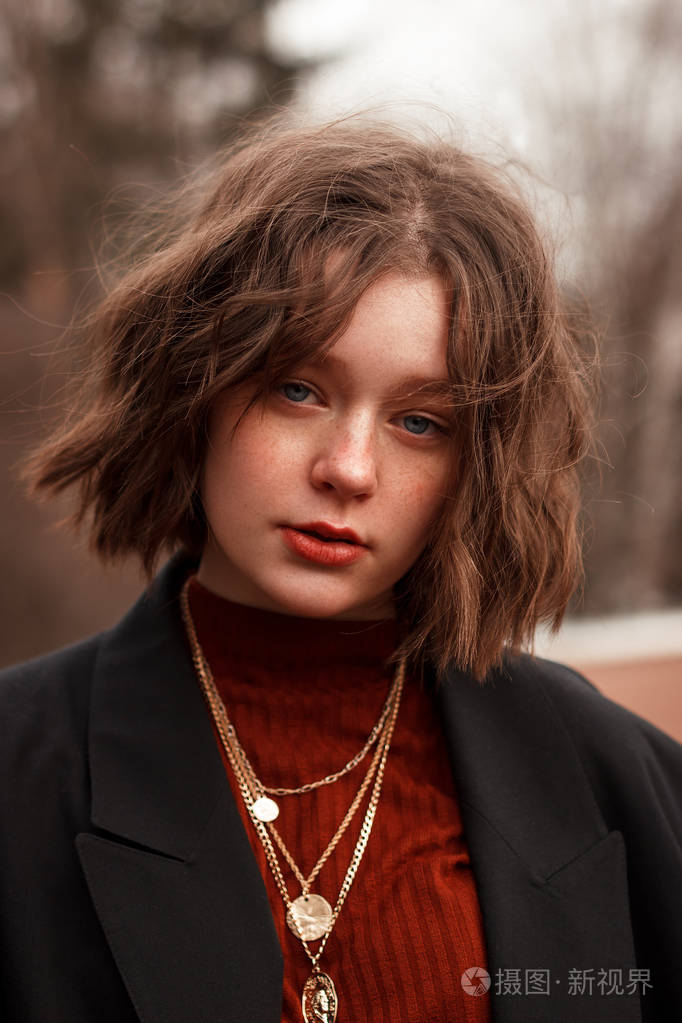 蓝色眼睛,红色嘴唇和雀斑的年轻卷发女孩的时尚肖像