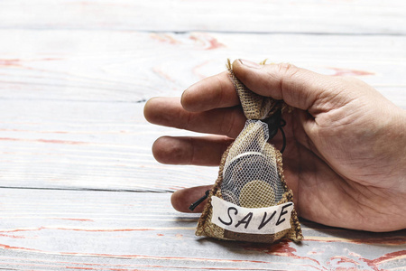 拥有现金带拉绳的小袋子. 男性手是一个普通的工人拿着它.