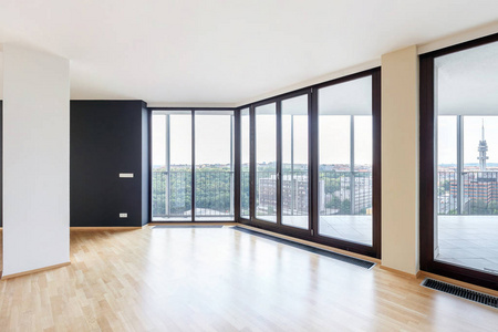 现代白色空阁楼公寓内部有镶木地板，黑色柱子和全景窗，俯瞰大都市