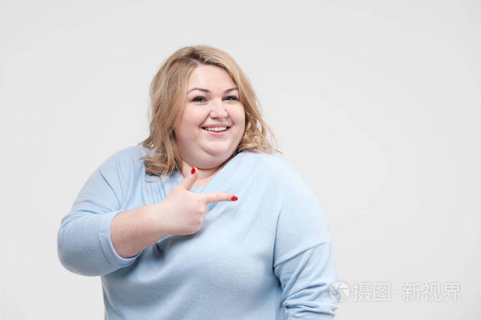 年轻的肥胖妇女在休闲蓝色衣服在白色背景在演播室身体阳性