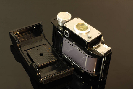 旧的老式相机和黑色镜子桌上的胶卷