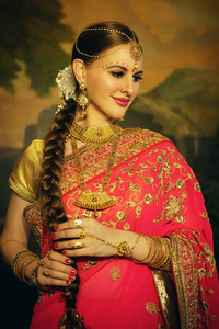 美丽的印度女孩在家里的肖像微笑。年轻的妇女模型与金黄珠宝集合