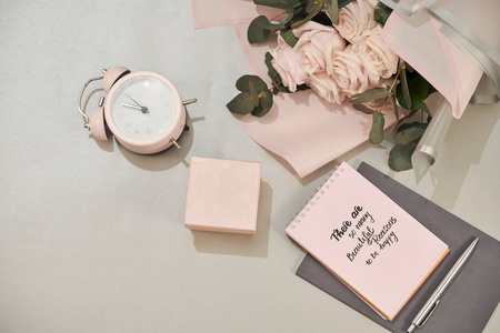 礼品盒闹钟和粉红色玫瑰花在白色桌面上，平躺风格。 母亲节或妇女节贺卡。