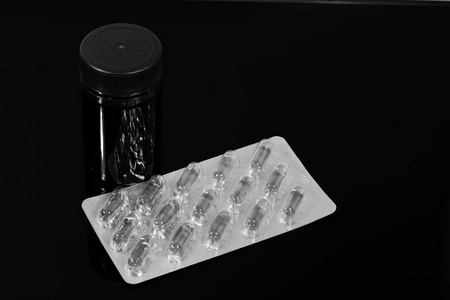 药片鱼油胶囊和一罐装在黑色镜子桌上的药片
