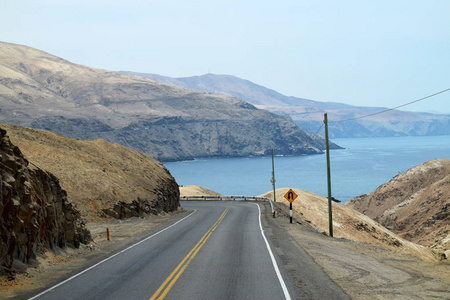 空旷的道路，背景是海洋和海岸线。 泛美公路在秘鲁拍摄的公路部分照片。