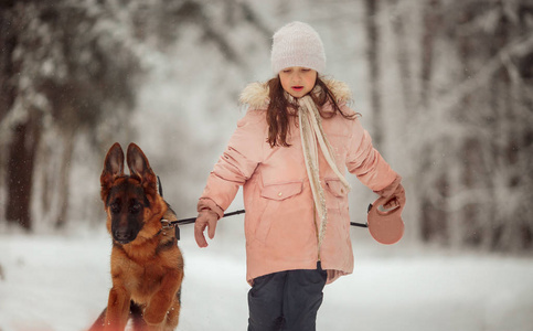 冬天森林里美丽的小女孩和小狗的肖像。