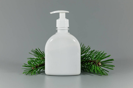 白色空白香水配药瓶，带有松树枝，灰色背景