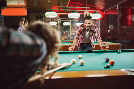 微笑的男人和朋友在酒吧玩池