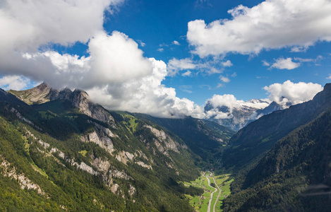 直升机在因特拉肯镇的瑞士阿尔卑斯山上行走。 俯瞰山谷高山和多云的天空。 瑞士