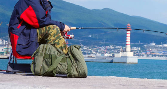一个拿着鱼竿坐在港口码头上的人。